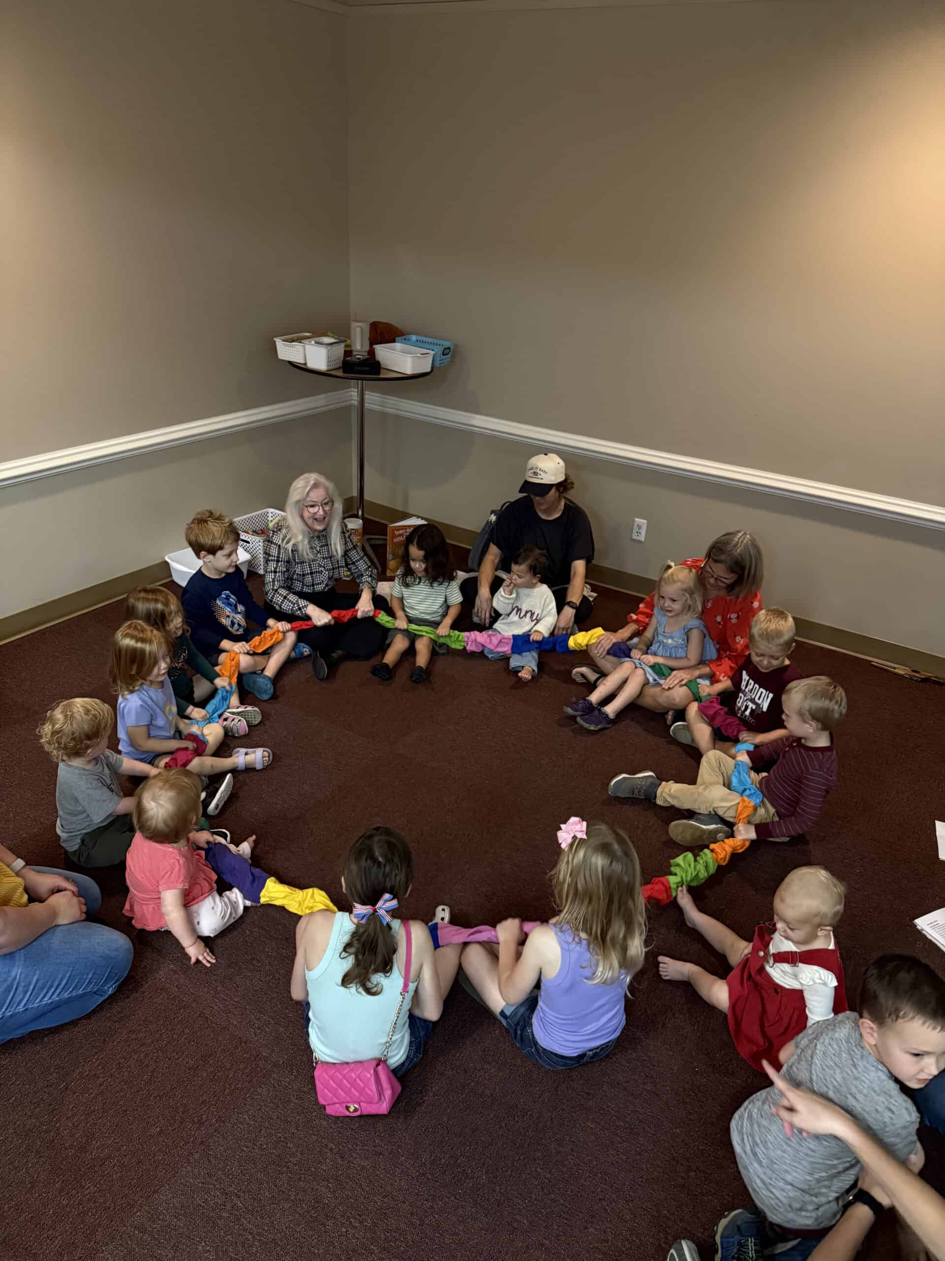 Bright children and adults sitting in a circle during a group activity at Saint Andrew's Episcopal C.